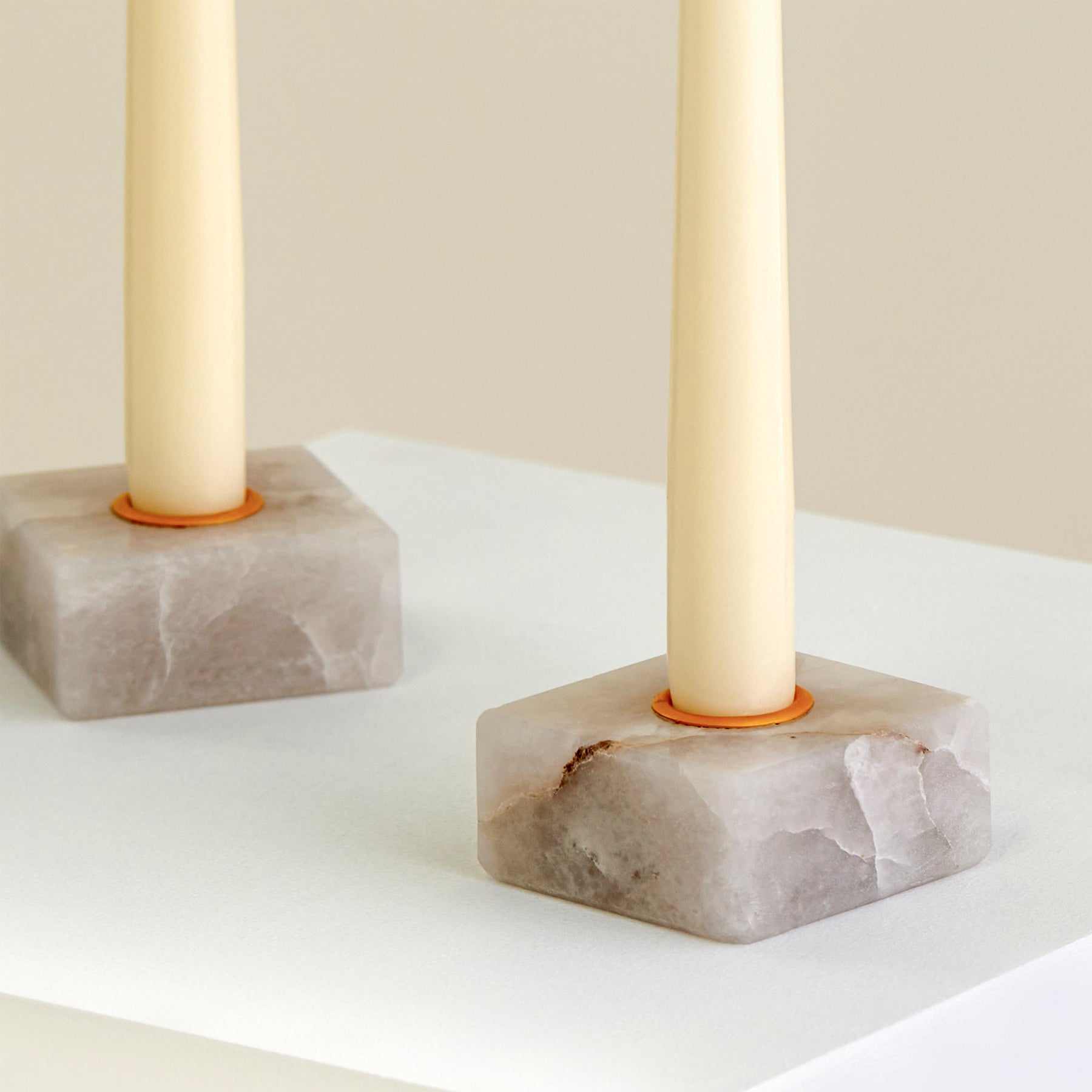 A close-up of two candle holders on a plinth made from Cristallo Imperial Onyx with gold detailing