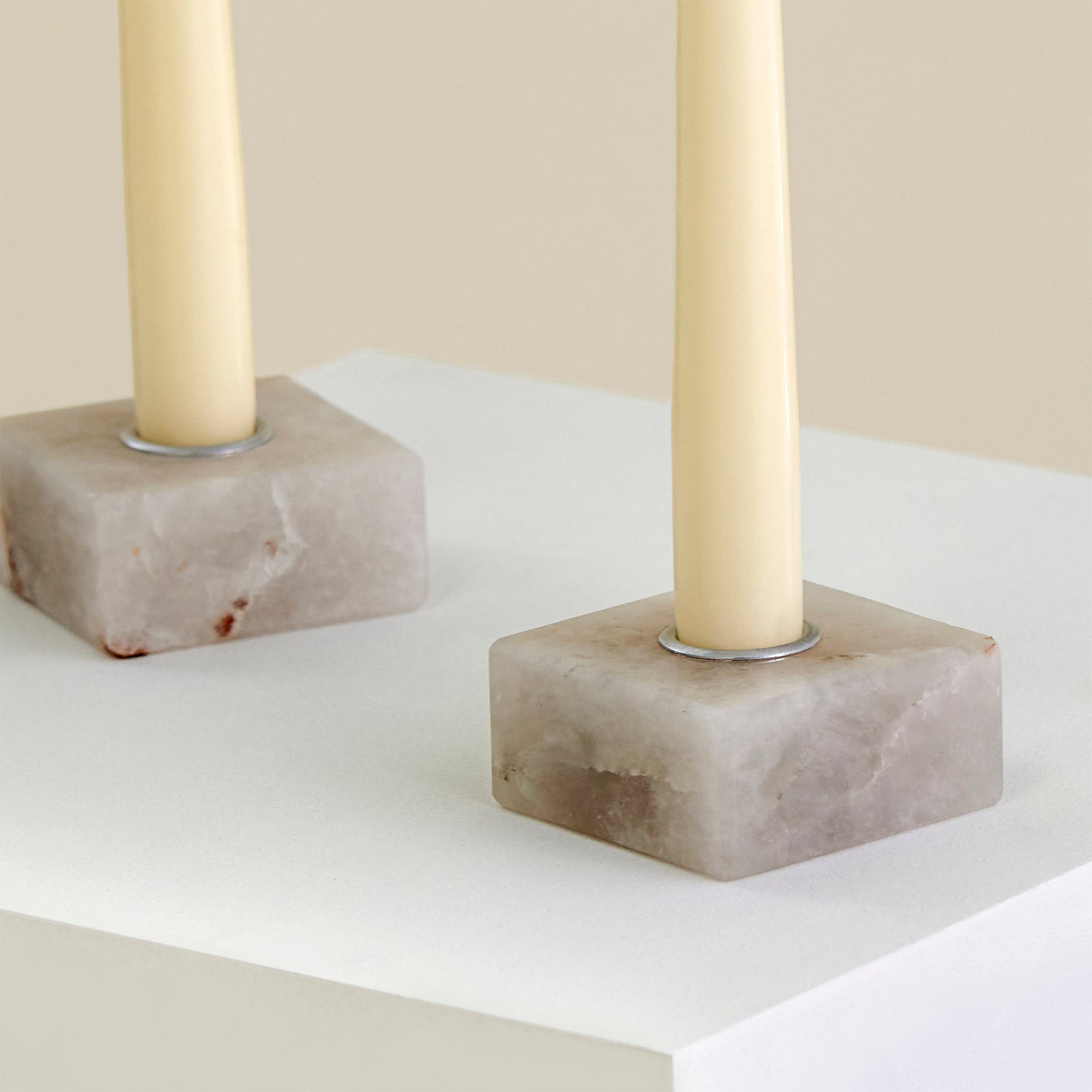 A close-up of two candle holders on a plinth made from Cristallo Imperial Onyx with silver detailing.