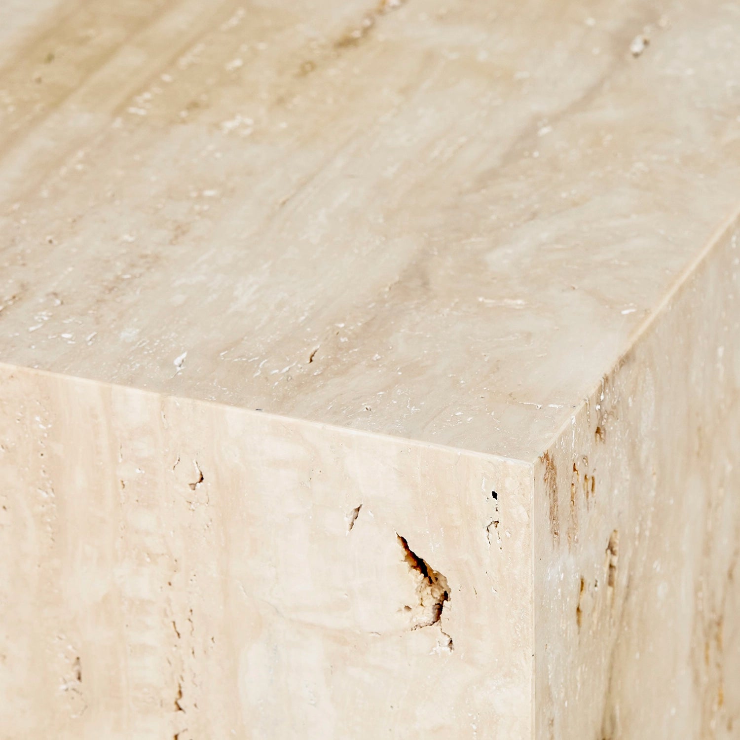 A close-up detail of a Fia travertine marble cube side table.