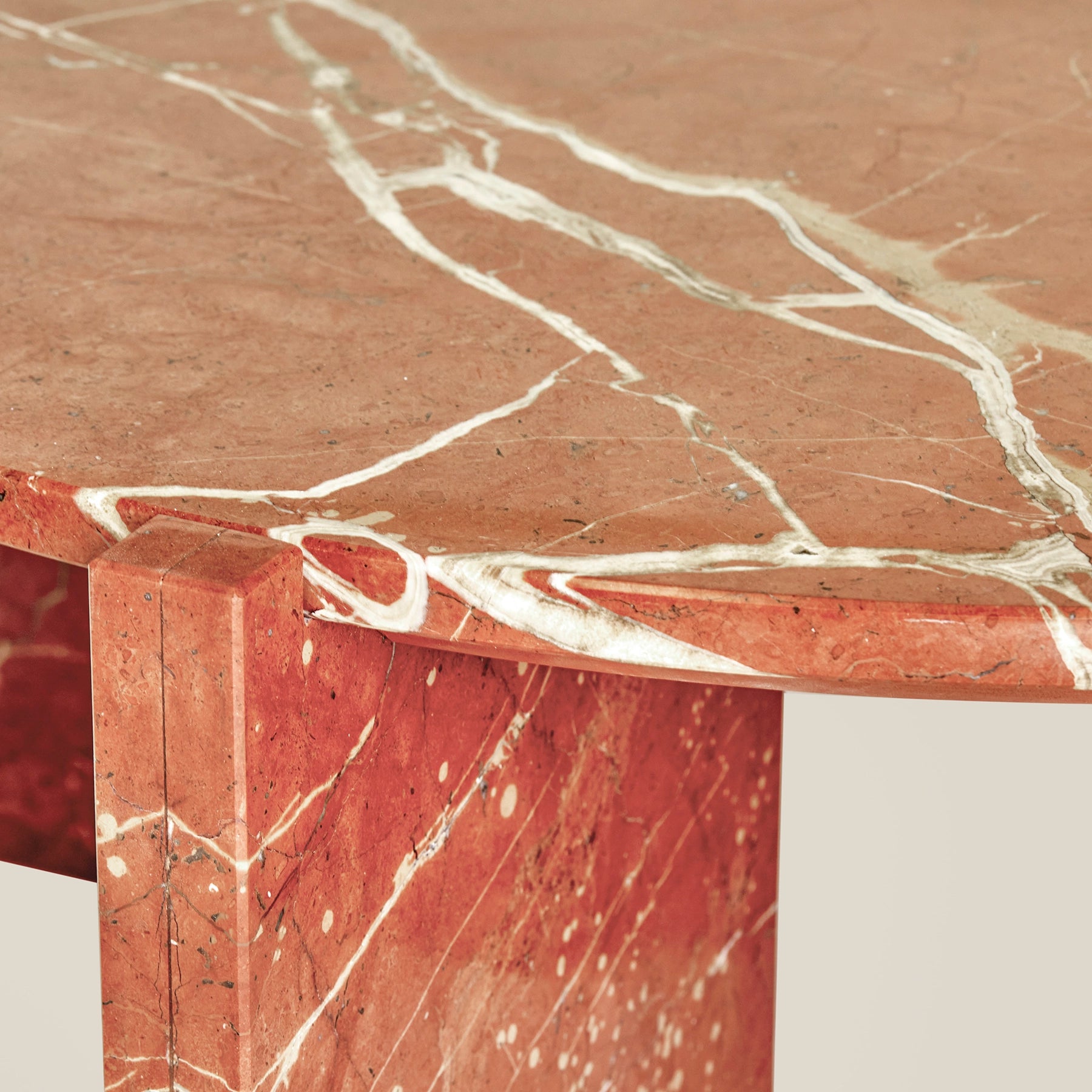 A close-up of the Gaia round coffee table made from Rosso Alicante marble.