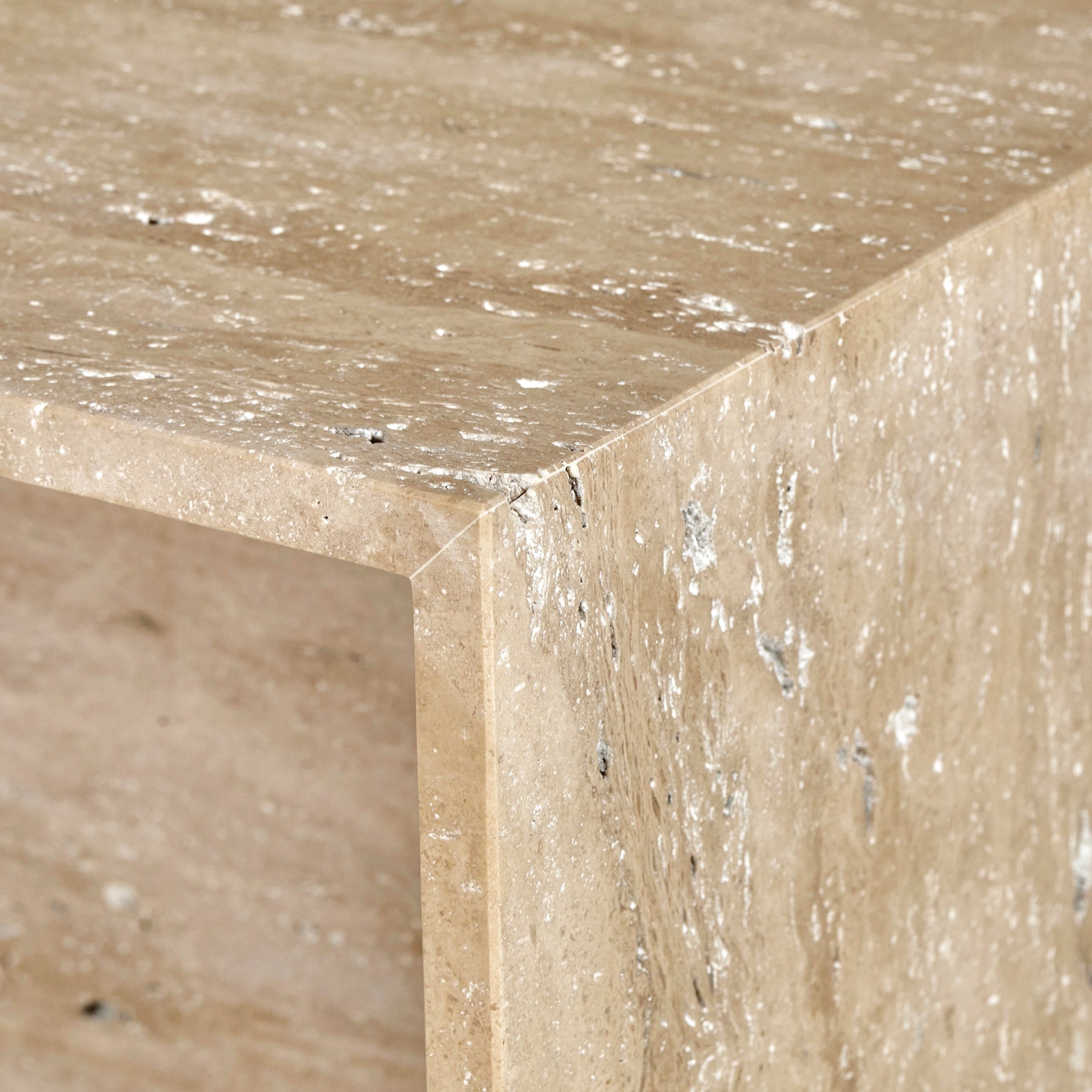 A close-up detail of a Gianna side table made from Travertine Romano marble.