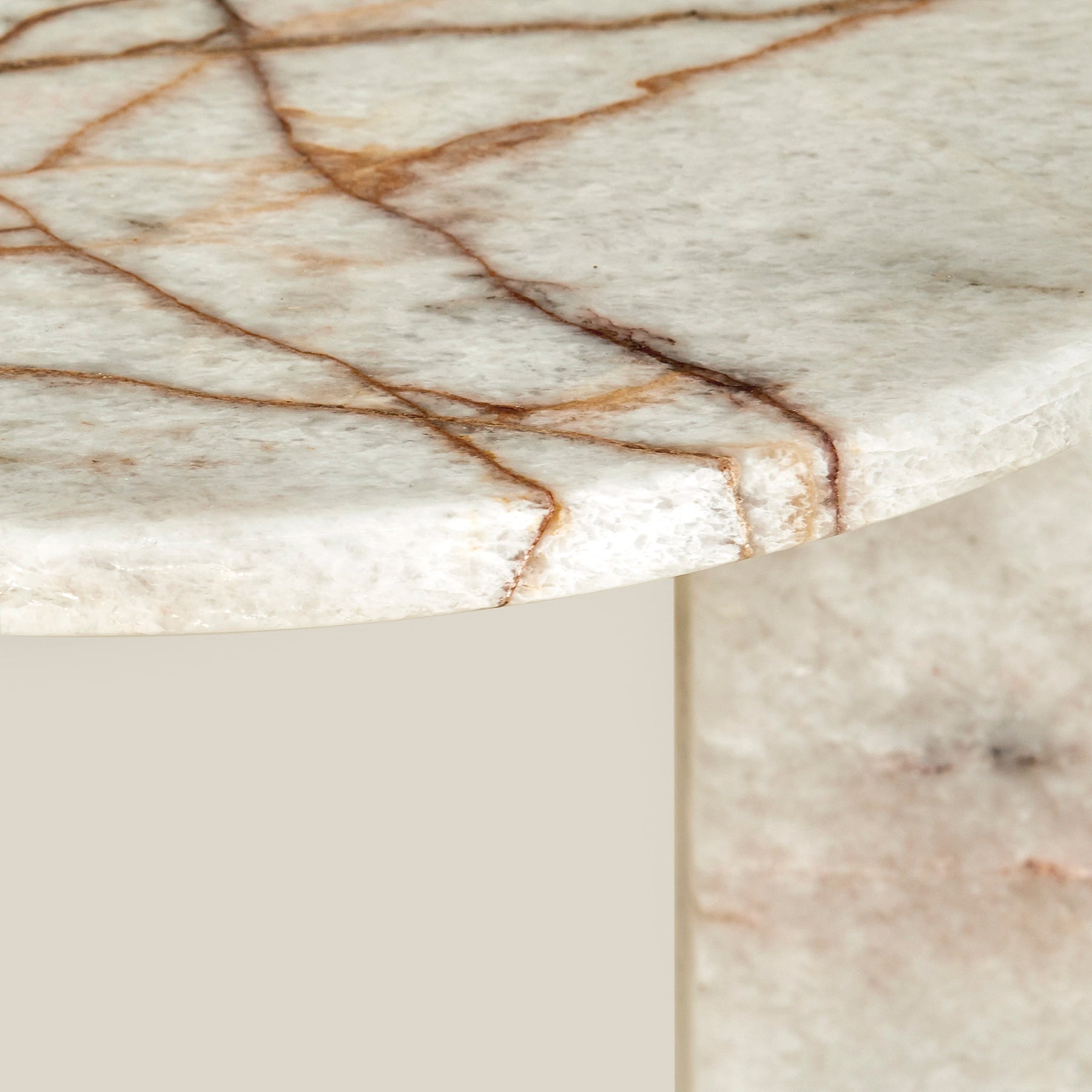 A close-up detail of a Minerva, a minimalistic, three-legged, round side table. Made from Cristallo Imperial marble.