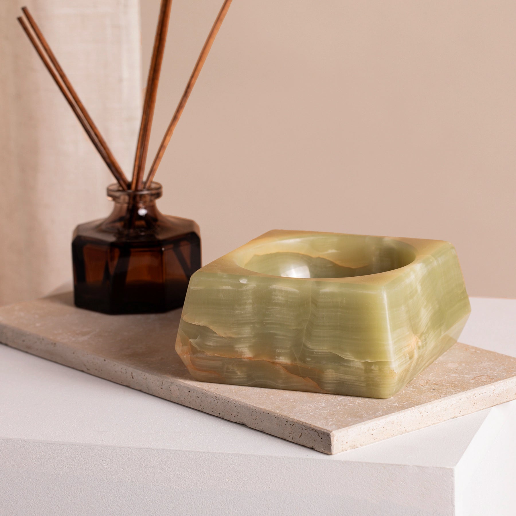 Green onyx jewellery holder on a marble tray  and plinth.