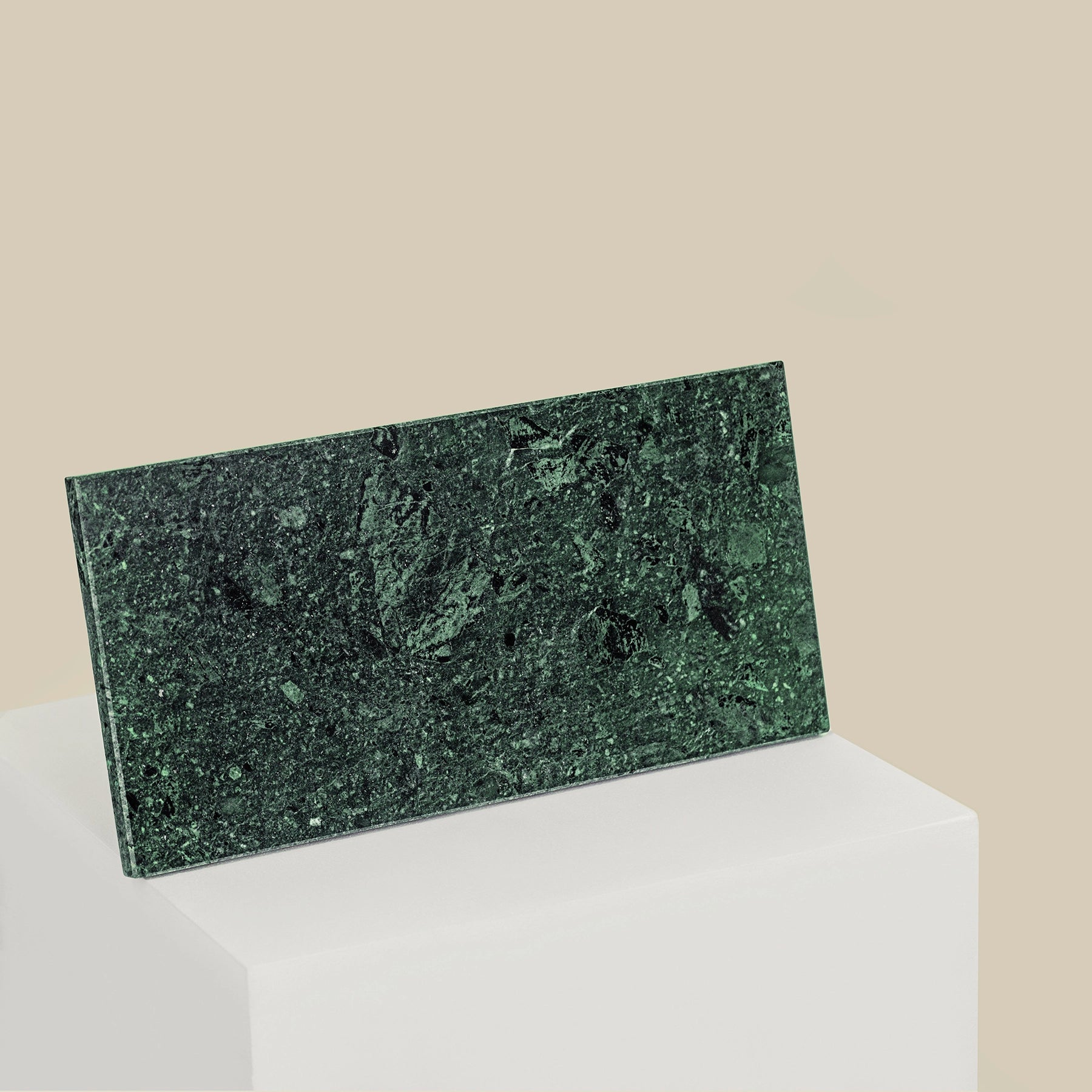 A rectangular, verde guatemala marble tray on a plinth, stood up on its side.