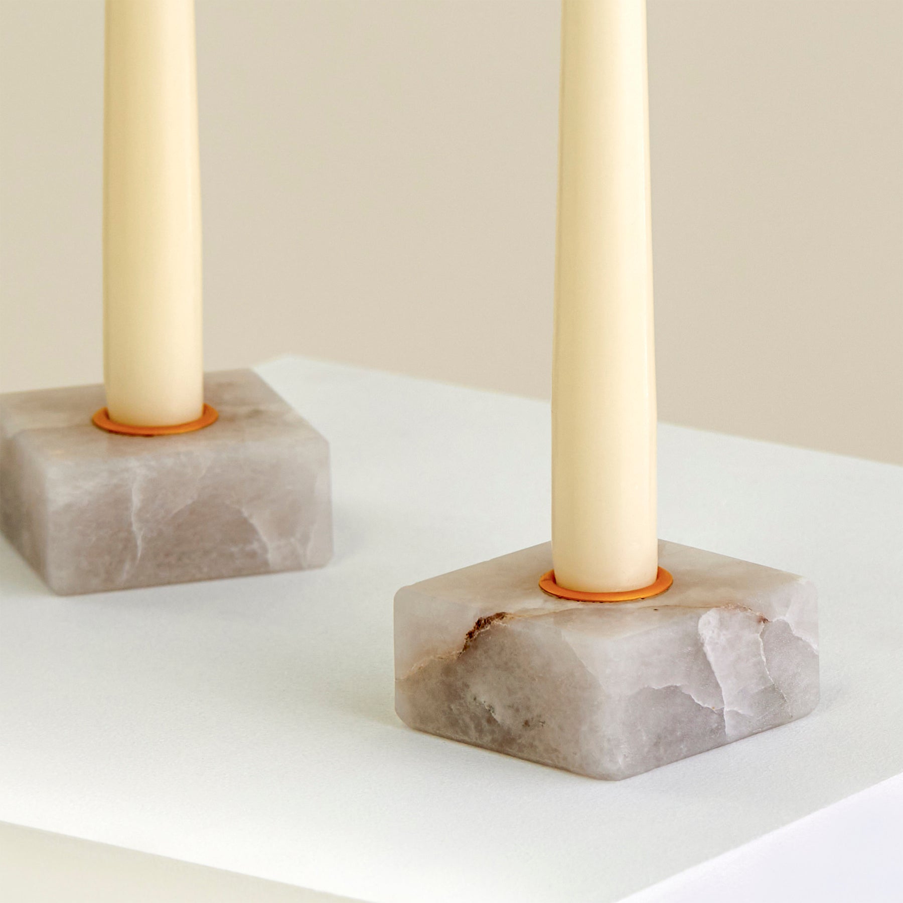 A close-up of two candle holders on a plinth made from Cristallo Imperial Onyx with gold detailing