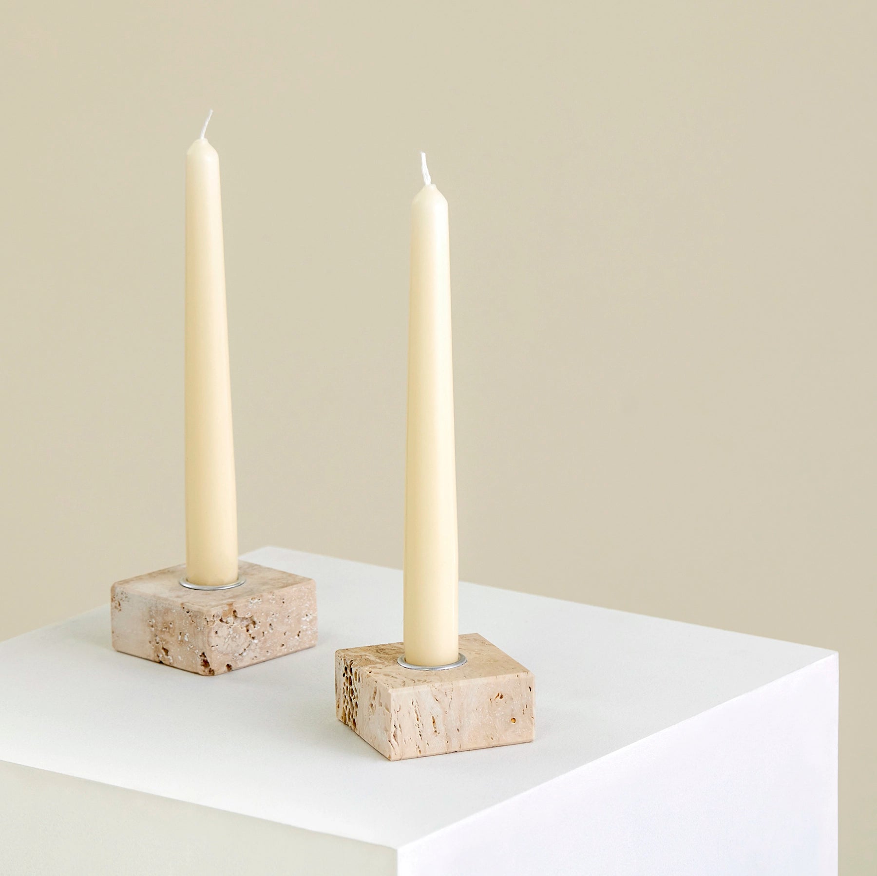 Two candle holders on a plinth made from Travertine marble with silver detailing.