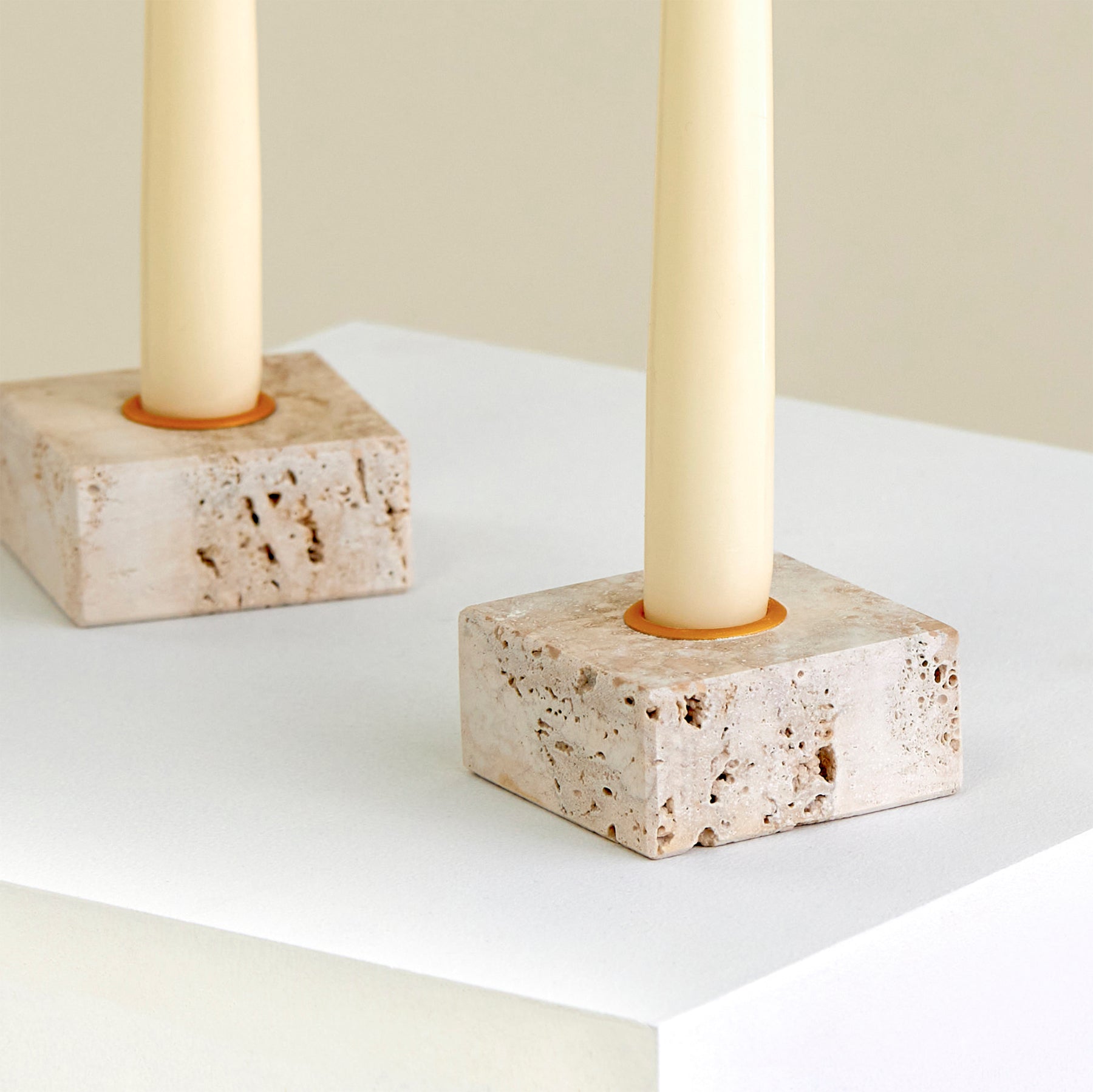 A close-up of two candle holders on a plinth made from Travertine marble with brass detailing.