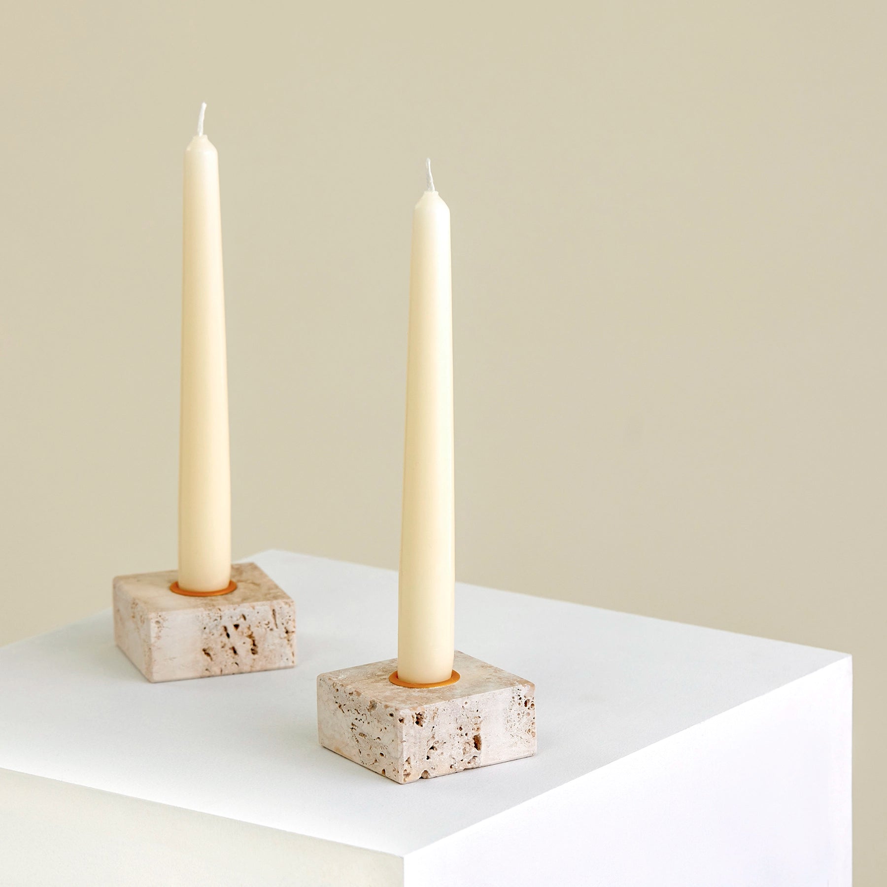 Two candle holders on a plinth made from Travertine marble with brass detailing.