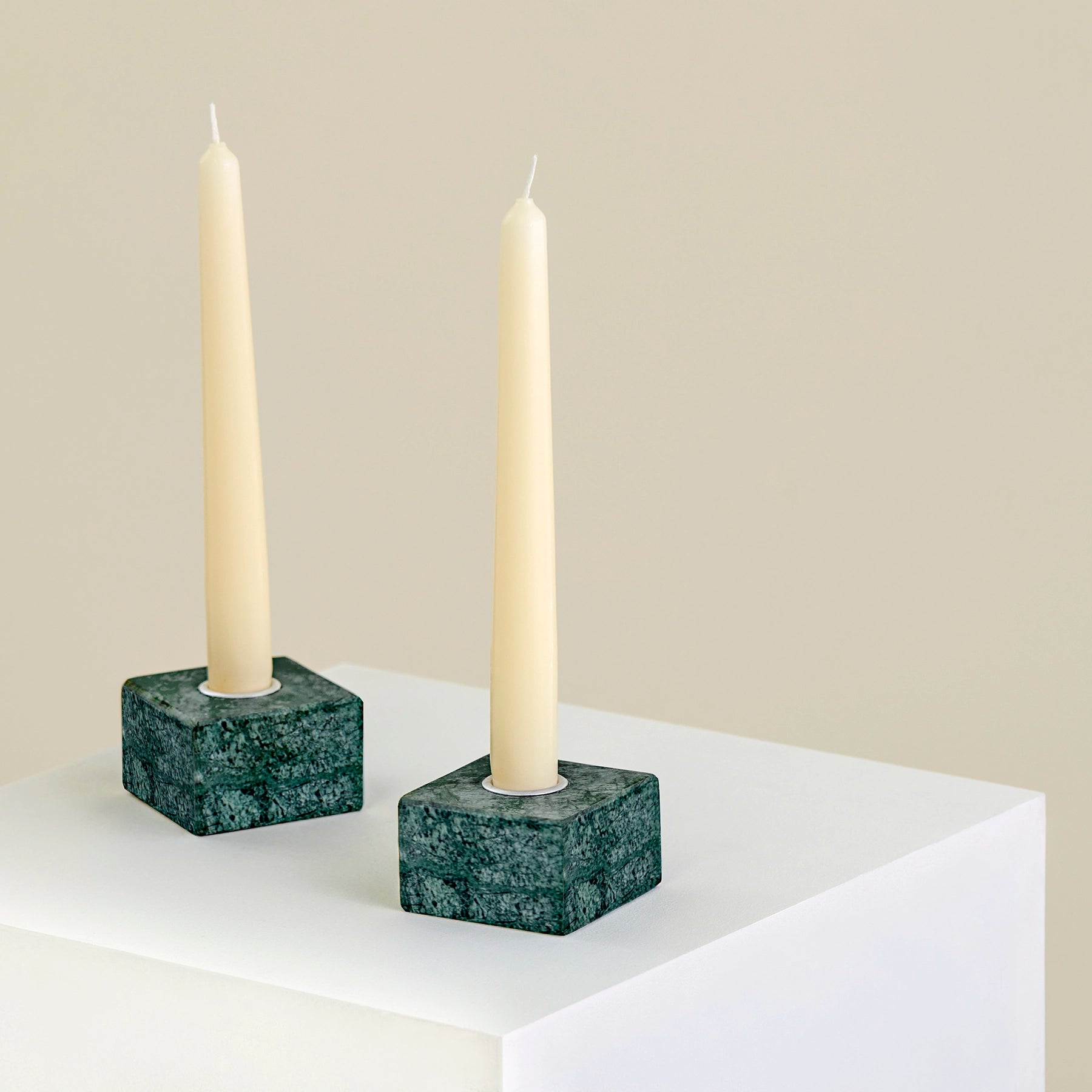 Two candle holders on a plinth made from Verde Guatemala marble with silver detailing.