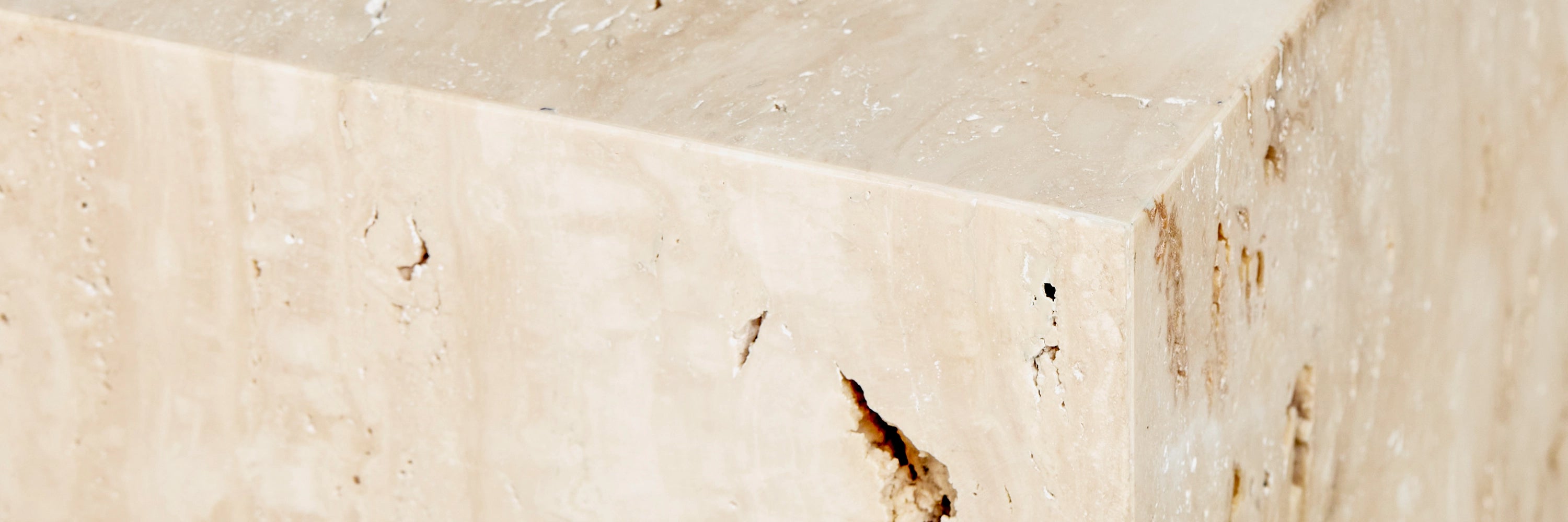 A close-up detail of a Fia Travertine marble cube side table.